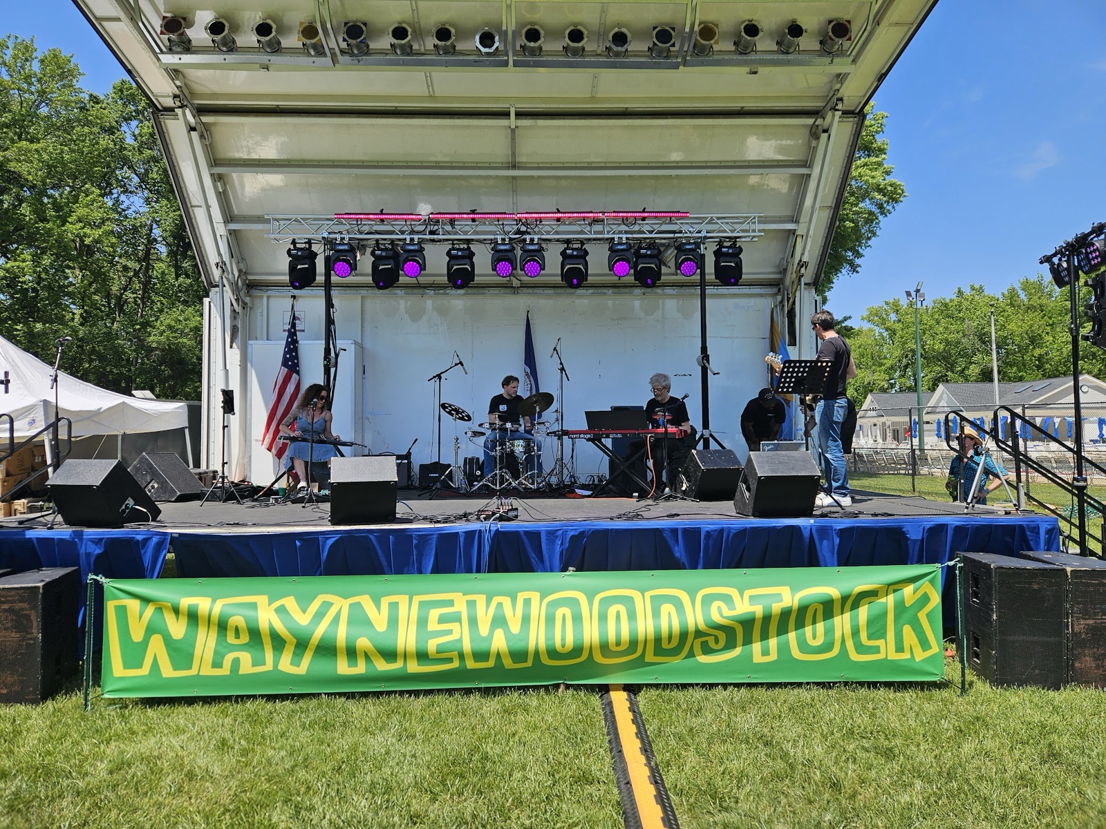 Establishing shot of the Waynewoodstock 2026 main stage with the WAYNEWOODSTOCK banner front and center