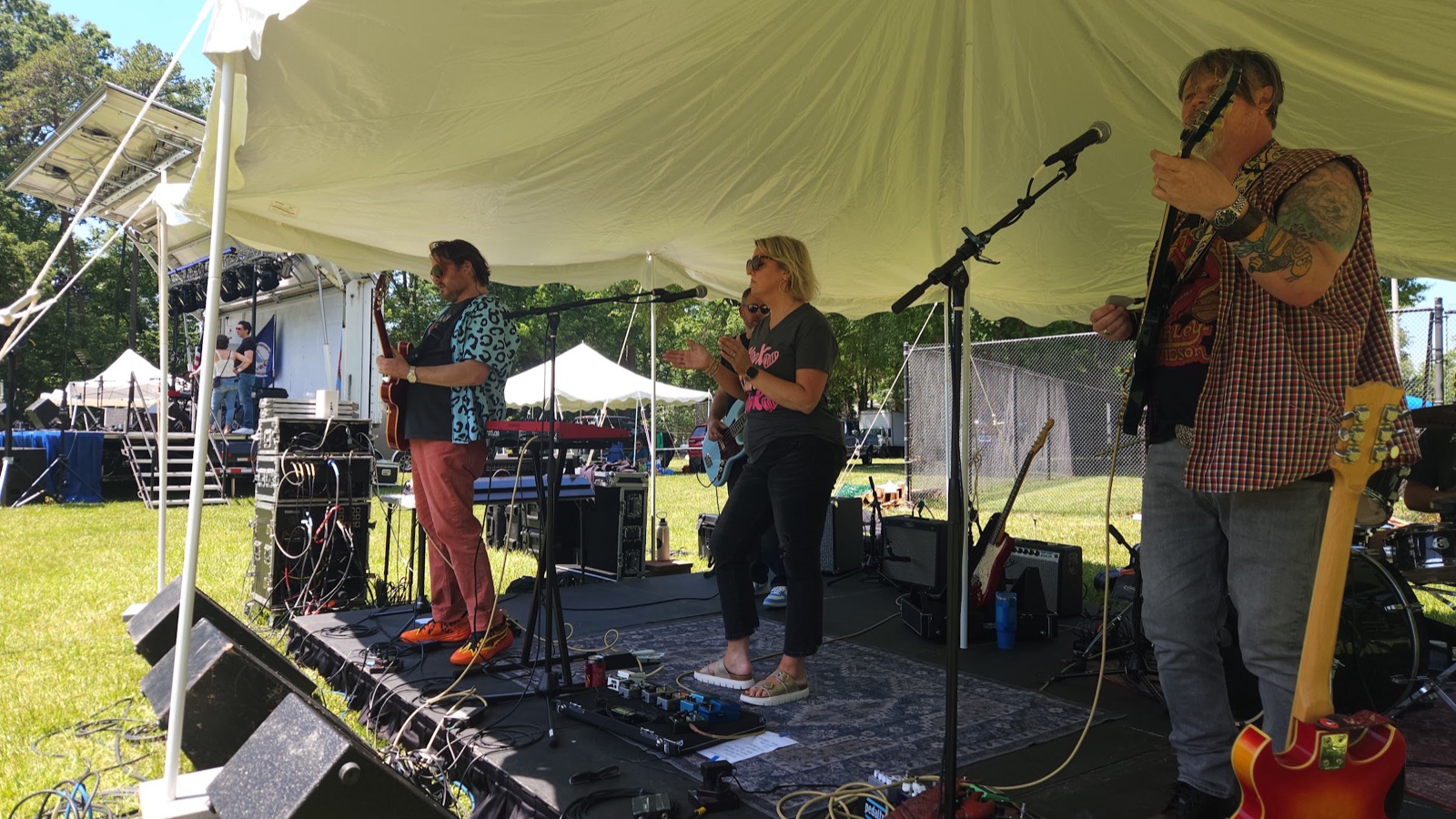 Band performing under the tent stage on a sunny afternoon at Waynewoodstock 2026