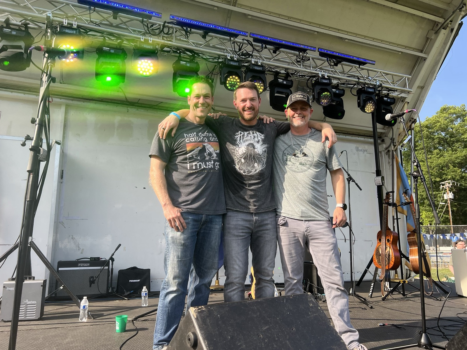 Three friends arm-in-arm on the Waynewoodstock 2026 main stage between sets