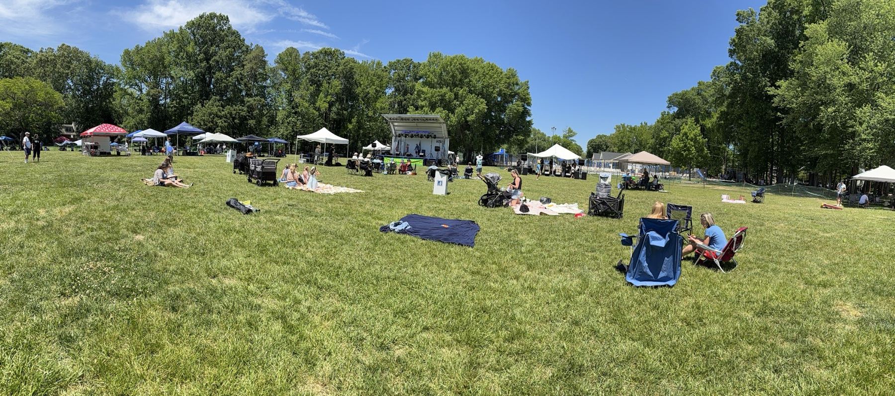 Wide view of Waynewoodstock 2026 — main stage, tents, and families spread across the field